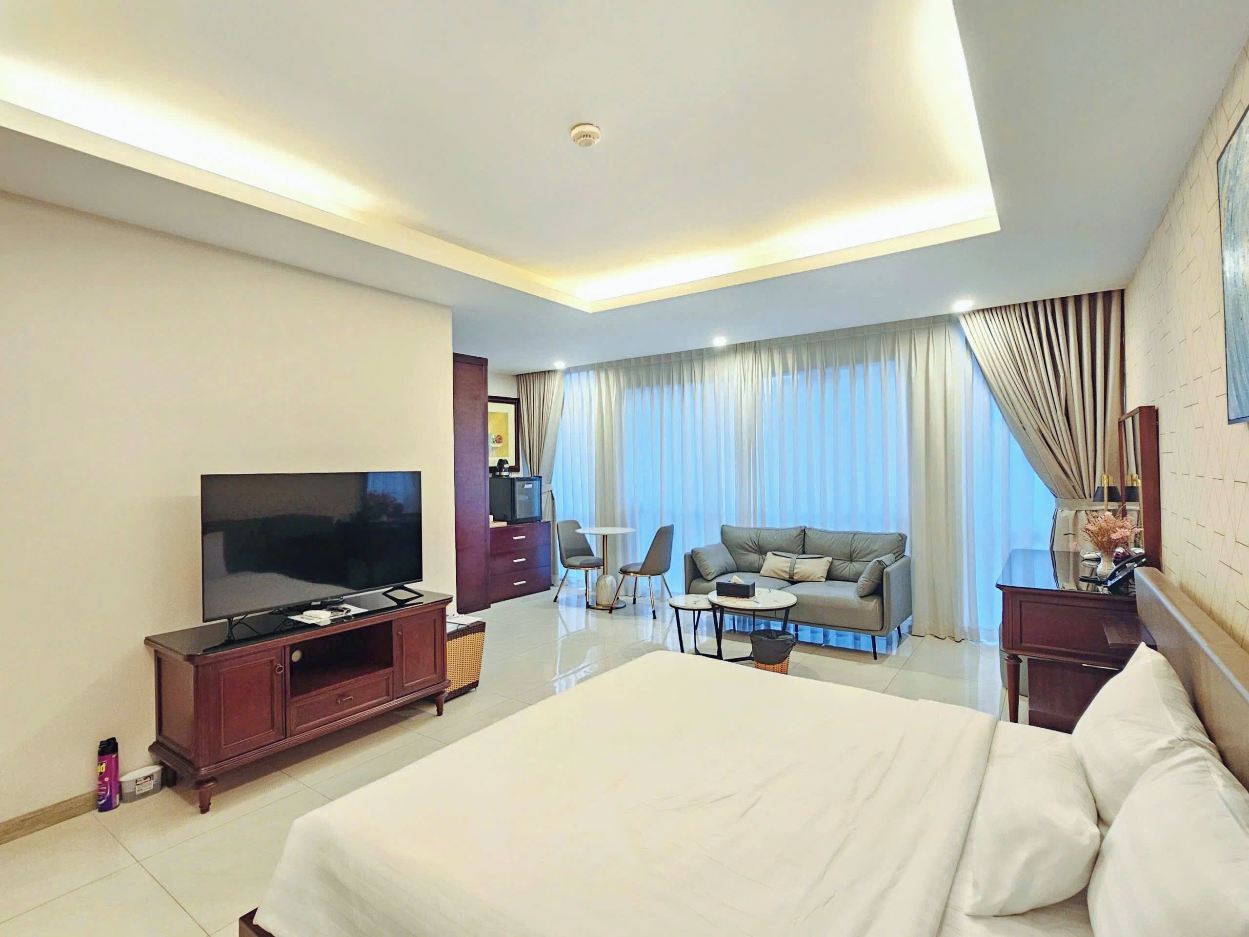 A hotel room with a bed, TV, seating area, and a dining table.