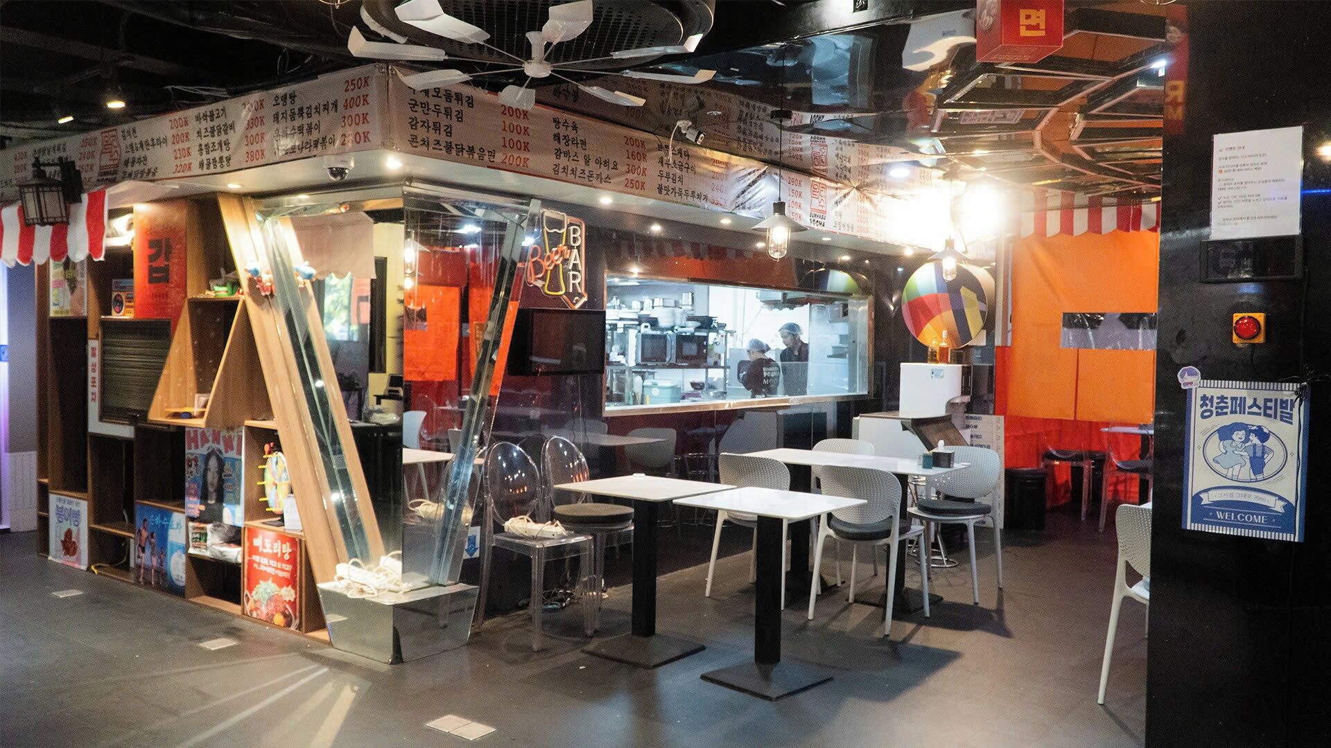 A restaurant with a glass enclosure, tables, chairs, and a counter visible through the glass.