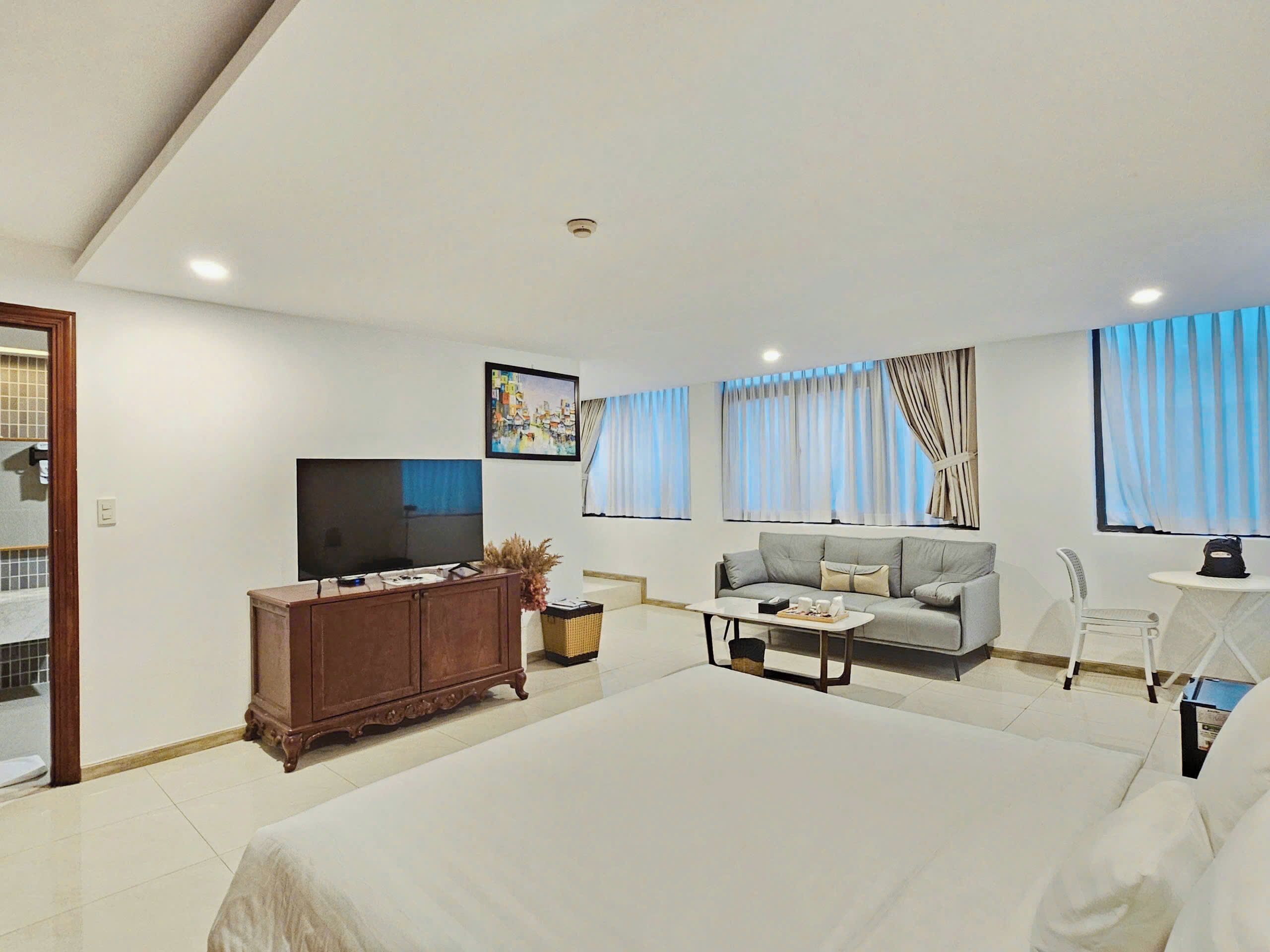 Quarto de hotel moderno com uma cama grande, um sofá, uma televisão e uma mesa de jantar.