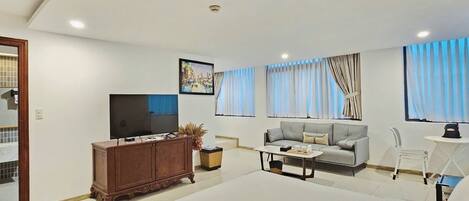 Quarto de hotel moderno com uma cama grande, um sofá, uma televisão e uma mesa de jantar.