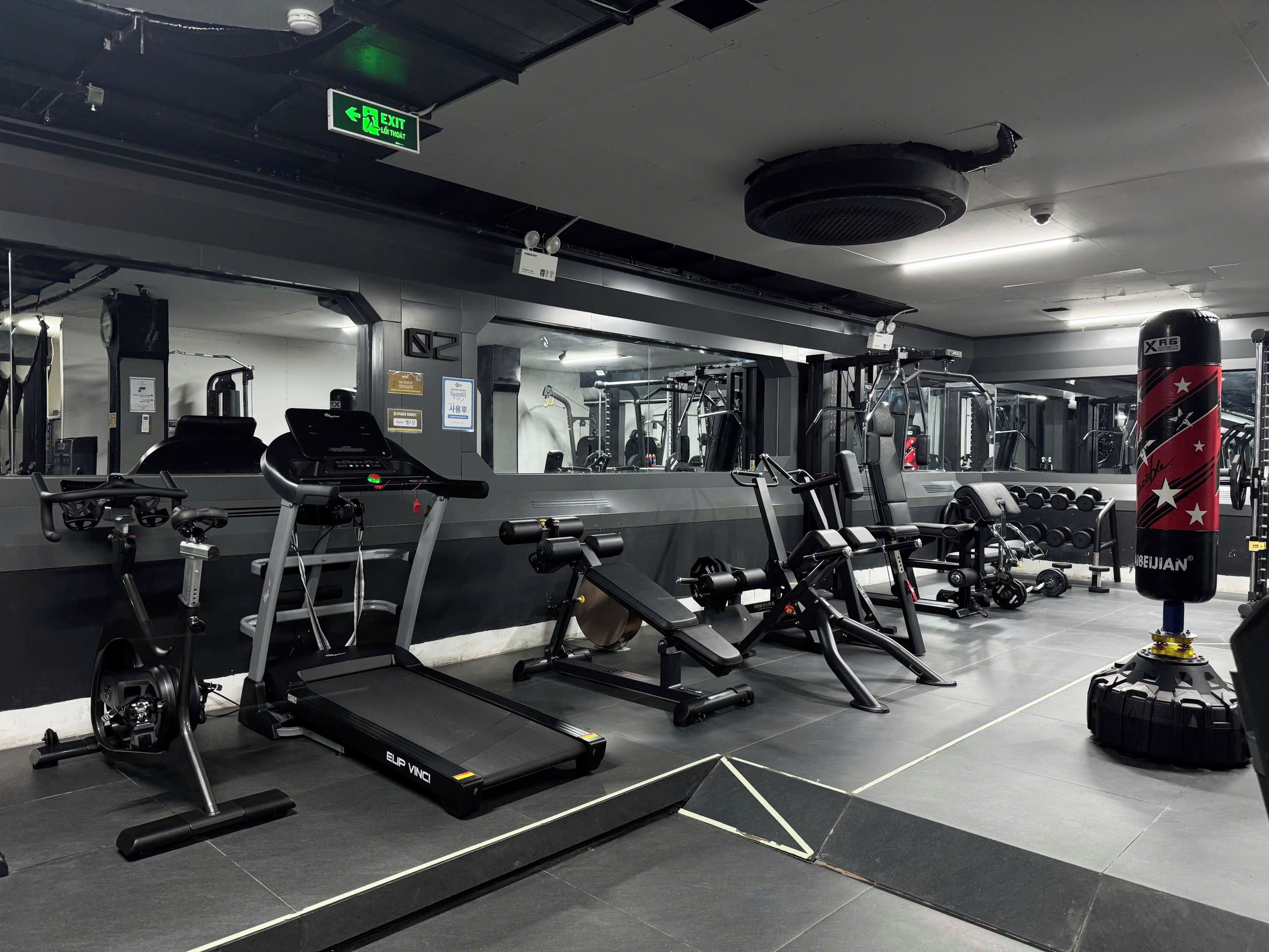 Ein Fitnessstudio mit Trainingsgeräten, einem Sandsack und einem Laufband.