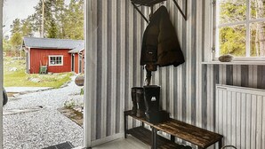 A room with striped wallpaper, a wooden bench, and a window with a view of a red building and trees.