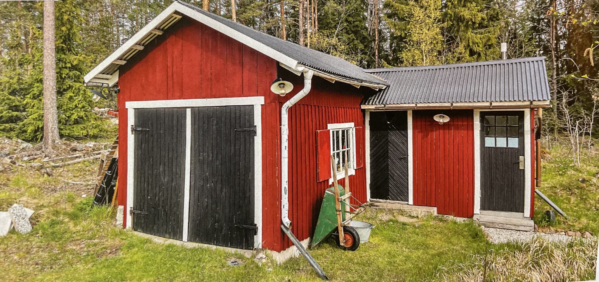 A red wooden building with a large garage door and a smaller attached shed.