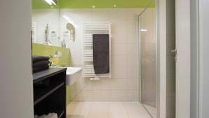A modern bathroom with a shower, sink, and mirror. - Herold RE-01 - Cozy vacation apartment The Remise Herold on Usedom with (Stolpe auf Usedom)