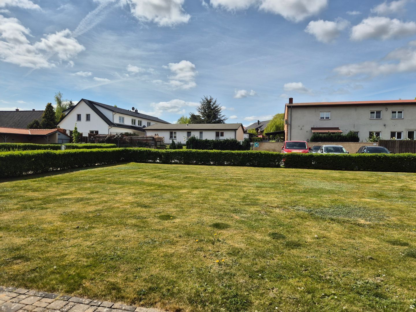 Un barrio residencial con casas, césped cuidado y coches aparcados.