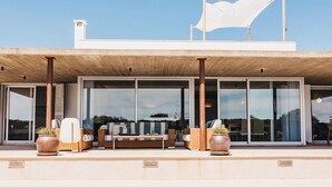 A modern house with a pool, large sliding glass doors, and outdoor seating. - My Rental Homes - Villa Neper with private pool, terrace and covered parking (Sant Lluís)