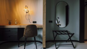 Un baño moderno con un tocador de madera, un espejo redondo y un perchero negro.