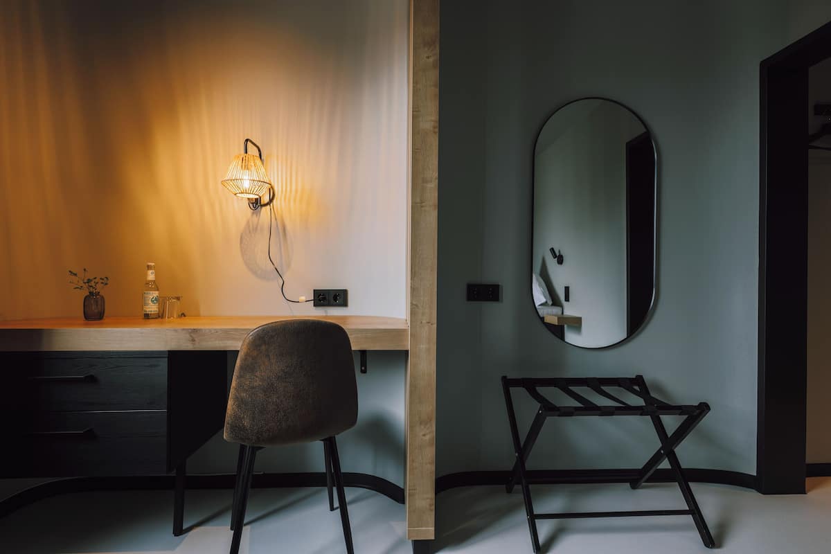 A modern bathroom with a wooden vanity, a round mirror, and a black towel rack.