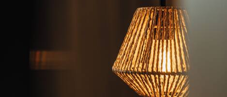 A close-up of a hanging lamp with a woven shade.