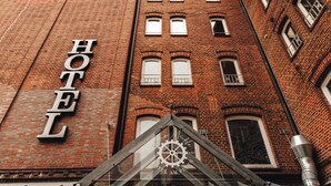 Un hotel con un llamativo letrero que dice 'HOTEL' en la fachada, un reloj grande y un distintivo símbolo de engranaje.