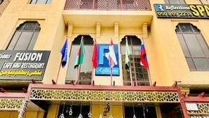 Een meerlaags gebouw met balkons, een café en restaurant genaamd 'Fusion', en een spa. Er wapperen vlaggen buiten.