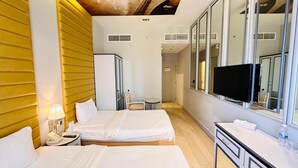 Een hotelkamer met twee bedden, een bureau met spiegel, een televisie, en een badkamer zichtbaar op de achtergrond.