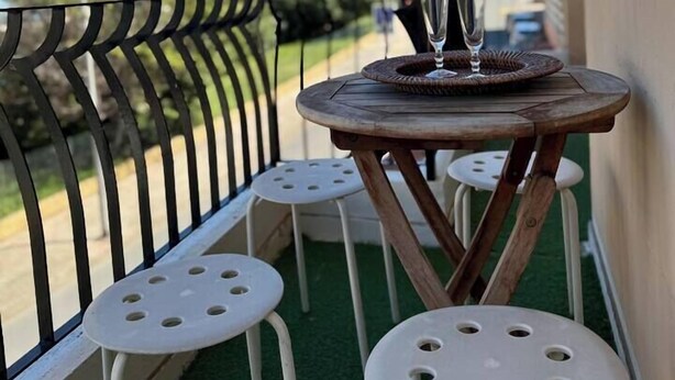 A balcony with a small round table and two white chairs, a wicker basket, and a glass on the table. - Escapade Provençale downtown (Saint-Raphaël)