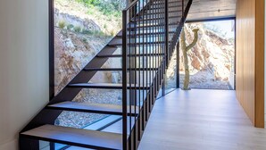A modern staircase with metal railings leading to an outdoor area with a rocky landscape. - My Rental Homes | Villa Mirante  with sea view and private pool (Begur)