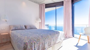 A bedroom with a large bed, a nightstand, a chair, and a view of the ocean through large windows. - My Rental Homes | Villa Mirante  with sea view and private pool (Begur)