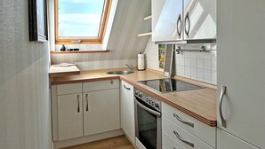 A modern kitchen with a skylight, white cabinets, a wooden countertop, and stainless steel appliances. - Eckhorst Farm, Landtraum (Güby)
