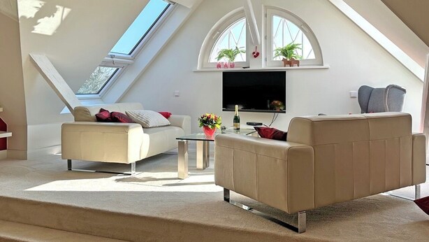 A modern loft-style living room with a high ceiling, skylight, and large windows. - Eckhorst Farm, Landtraum (Güby)