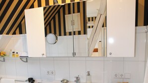 A modern bathroom with a large sink, white cabinets, and a striped wall design. - Eckhorst Farm, Landtraum (Güby)
