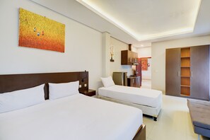 A hotel room with two beds, a kitchenette, a wardrobe, and a painting on the wall. - Collection O Bali near Sanur Beach formerly Akarsa Transit (Denpasar)