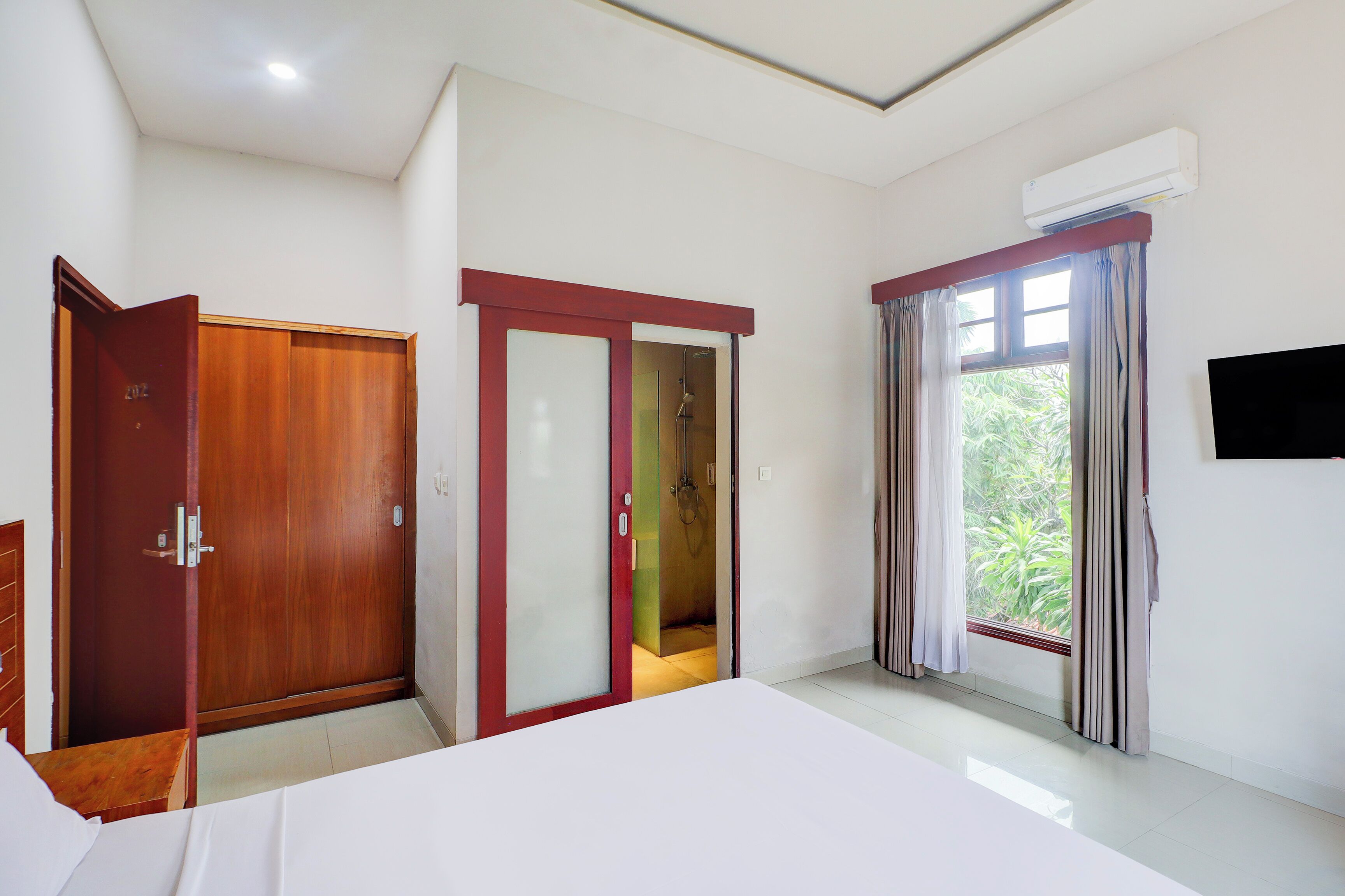 Een hotelkamer met een bed, een kledingkast, een douche en een raam met gordijnen.