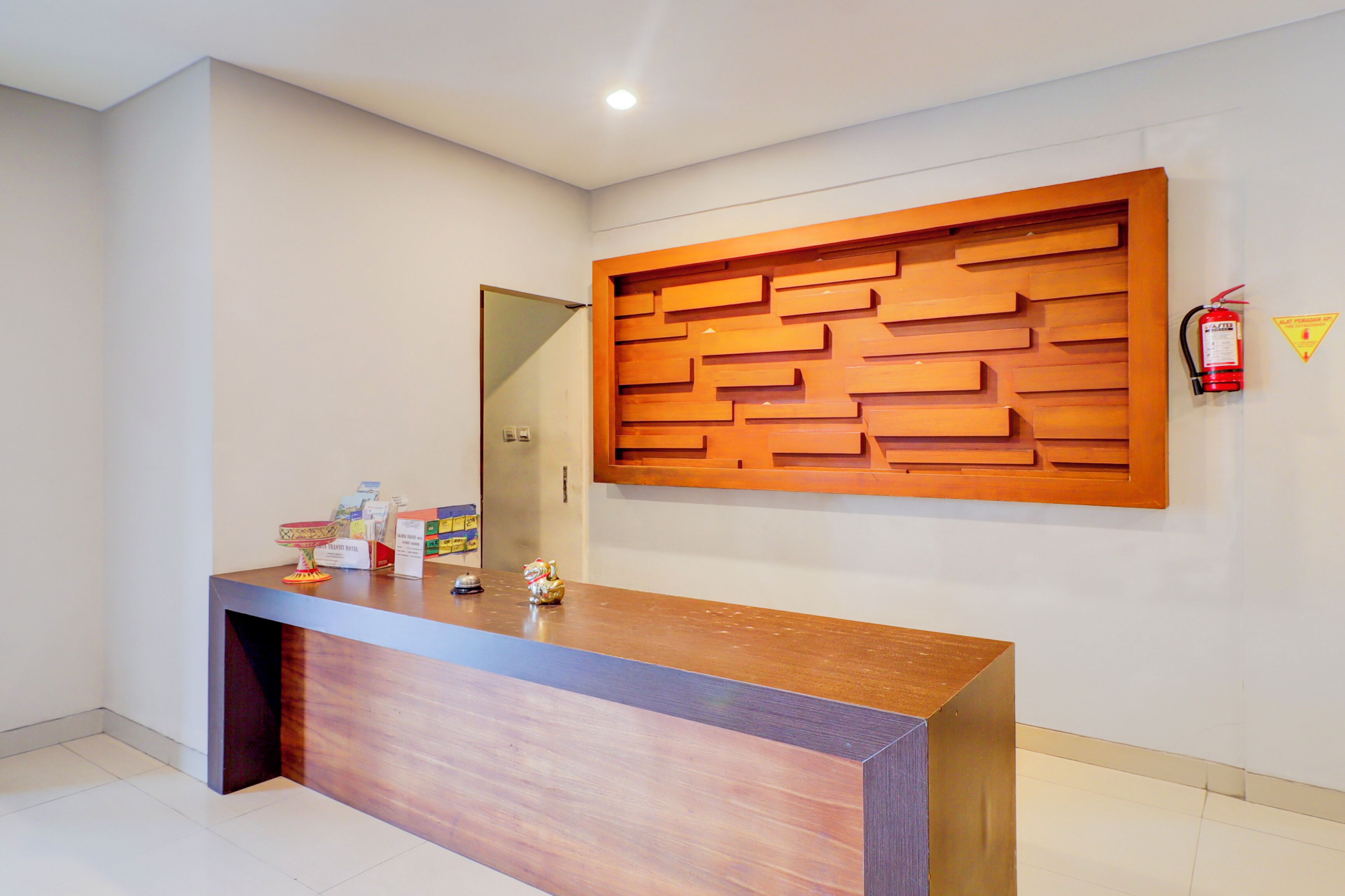 A reception desk with a wooden panel design, a fire extinguisher, and a caution sign on the wall.