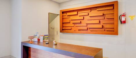 A reception desk with a wooden panel design, a fire extinguisher, and a caution sign on the wall.