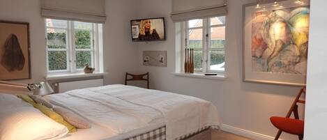 A bedroom with a bed, a chair, a desk, and a painting on the wall.
