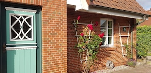 Ein Ziegelhaus mit grüner Tür, weißen Fensterrahmen und einer Ziegelwand.
