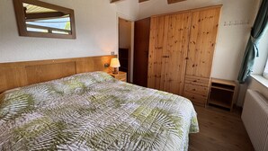 Ein Schlafzimmer mit einem Bett, einem Holzschrank und einem Nachttisch mit Lampe.