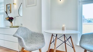 Ein modernes Interieur mit zwei grau gepolsterten Sesseln, einem weißen runden Tisch mit Kerze und einer Wandleuchte.