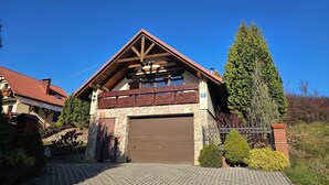 A two-story house with a stone facade, a brown garage door, and a red roof.