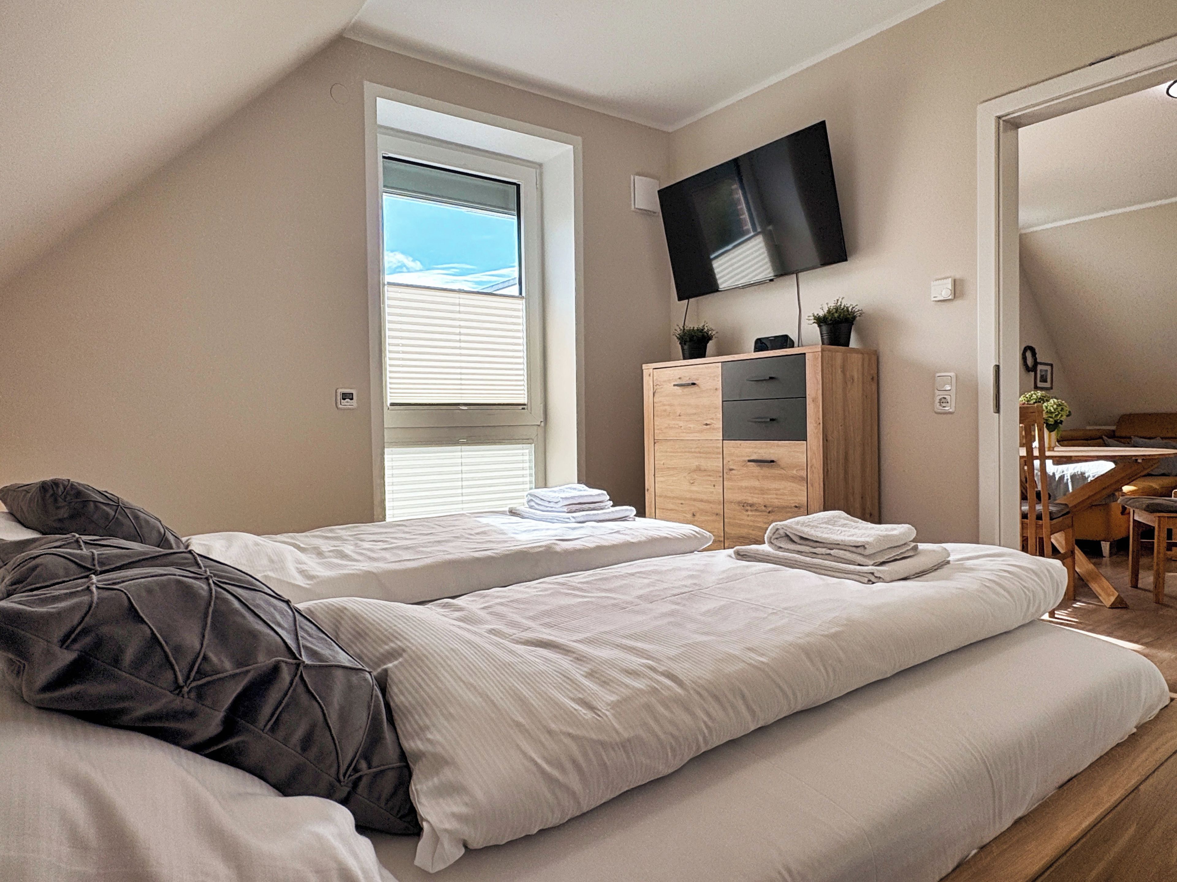 Ett hotellrum med två sängar, en TV, ett träskåp och ett skrivbord med en stol.