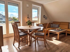 A cozy living room with a round wooden table, two chairs, a sofa, and a coffee table.