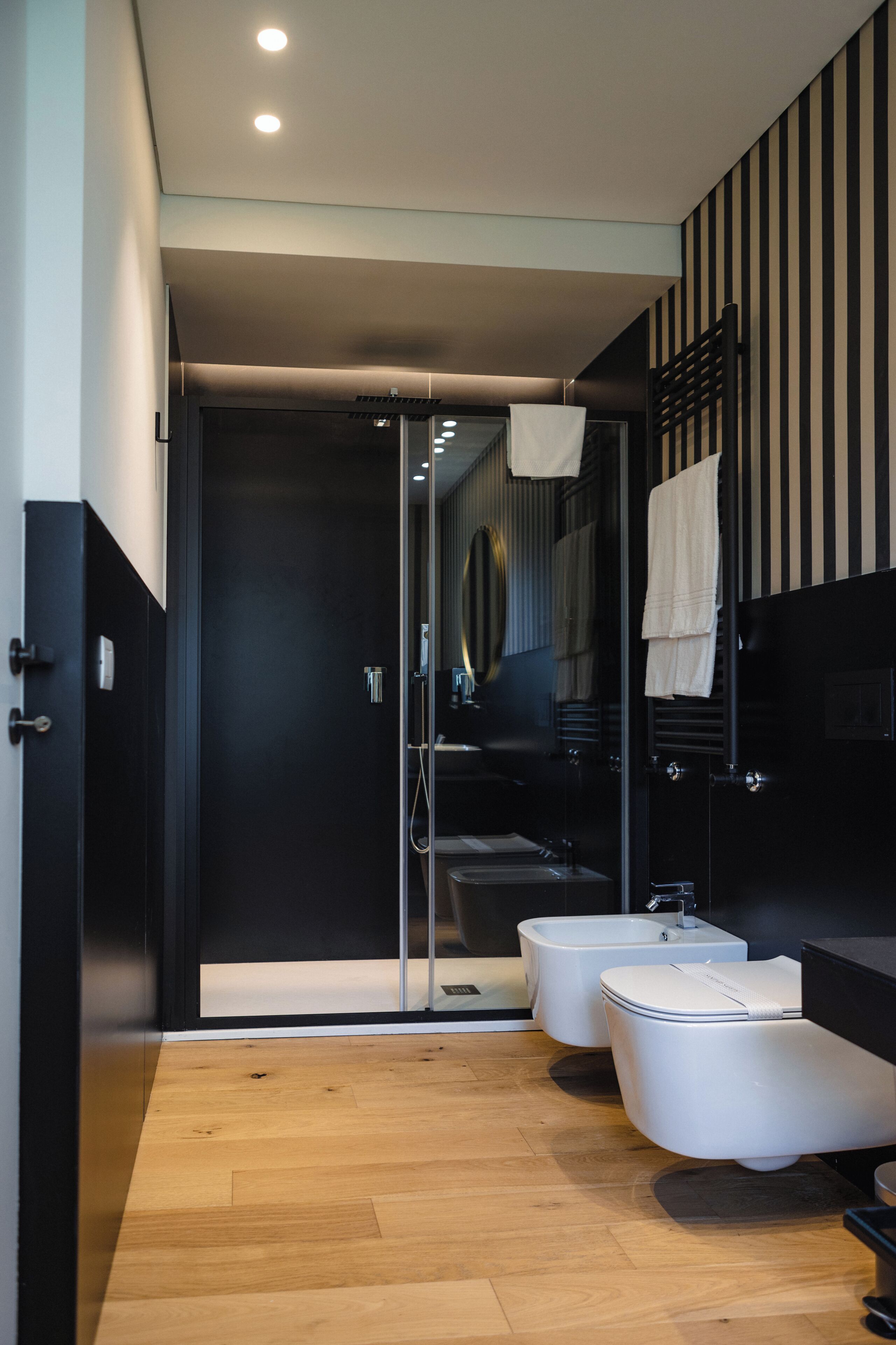 A modern bathroom with a shower, two toilets, and a sink.