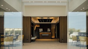 Ein Empfangsbereich mit modernem Design, der eine Rezeption, eine Sitzecke und einen Blick durch Glastüren bietet.