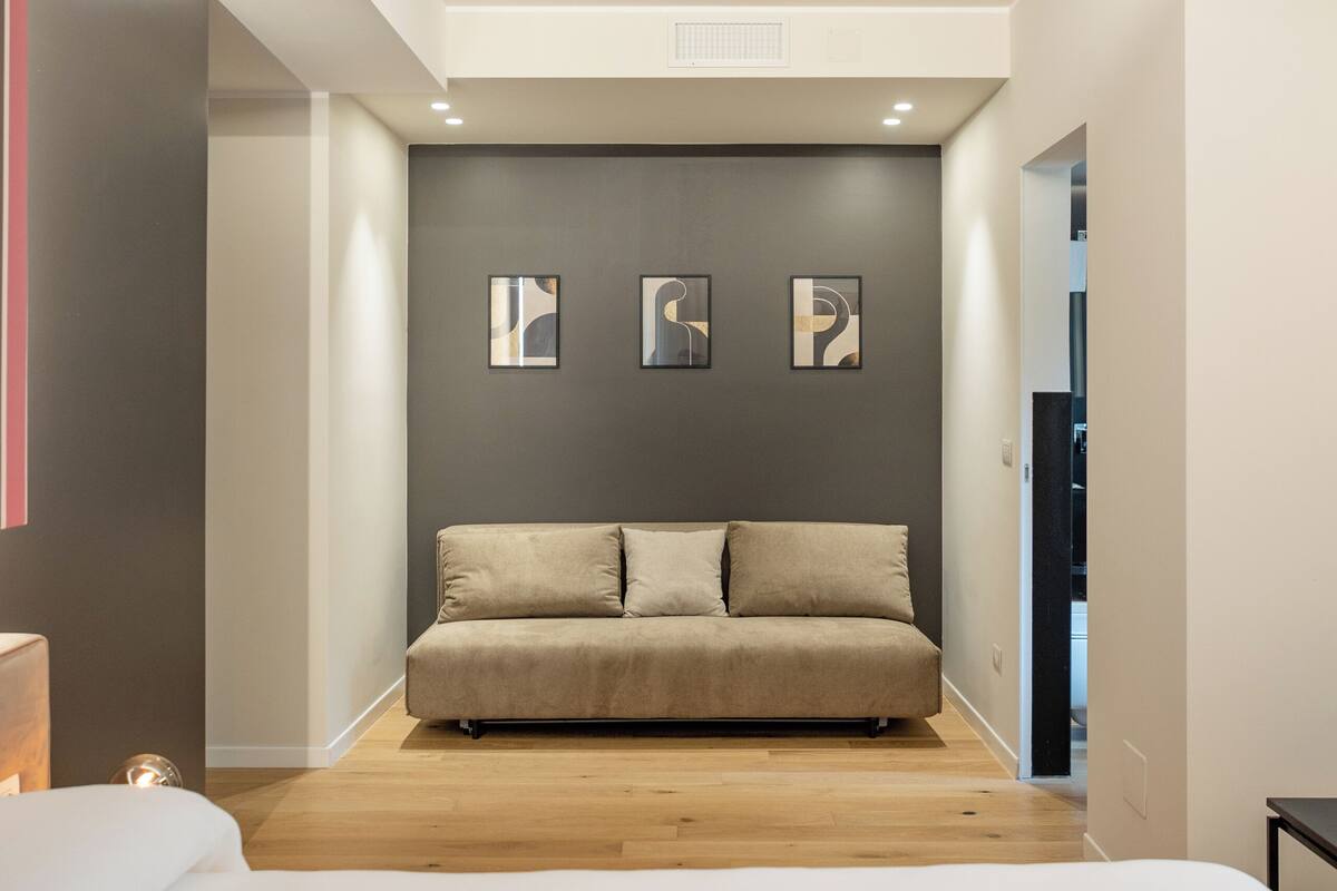 Une chambre moderne avec un grand lit, un canapé et trois œuvres d’art abstraites accrochées au mur.