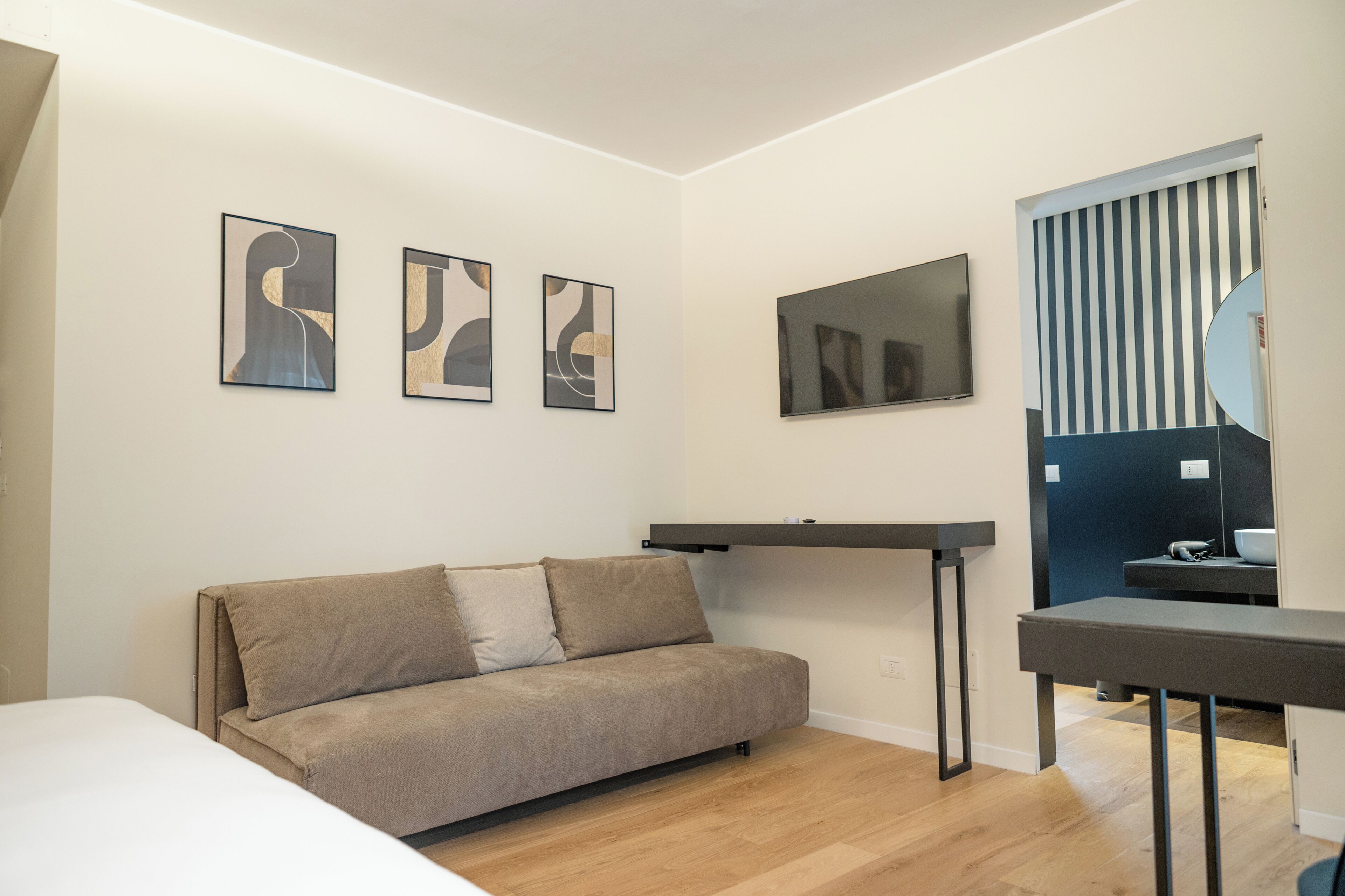 Una habitación moderna con sofá, televisor de pantalla plana y arte abstracto en la pared.