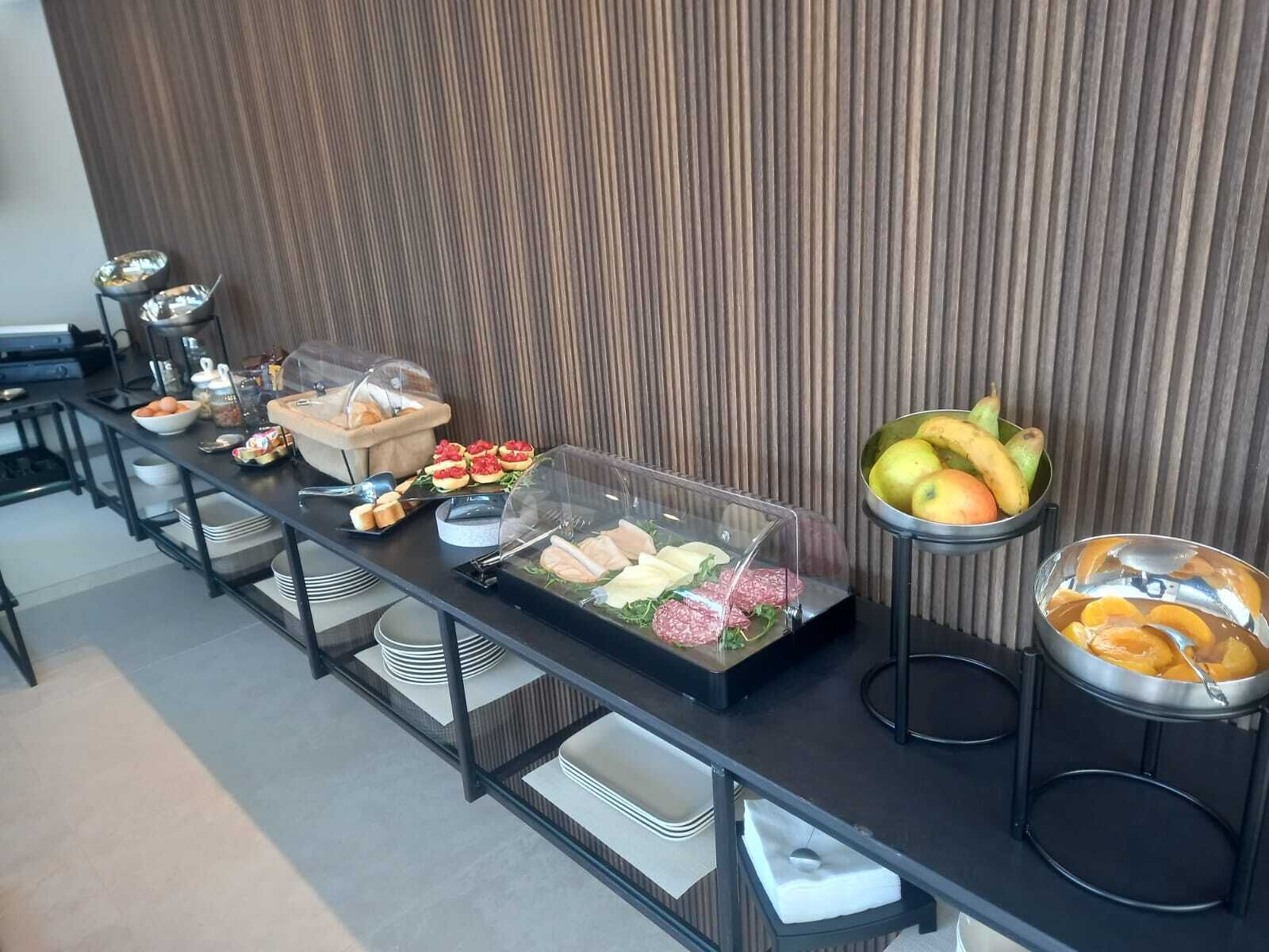 A buffet setup with various food items and a fruit bowl.