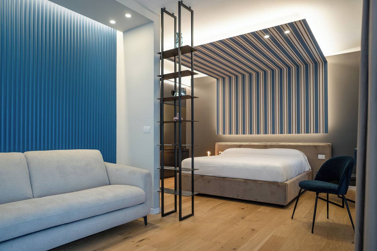 Une chambre moderne comprenant un canapé, un lit, une chaise et une étagère fixée au mur.