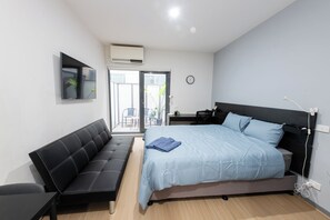 A bedroom with a bed, a sofa, a desk, and a chair. - Melbourne Studio Apartments Hotel @ 138 Elgin Carlton (Carlton)