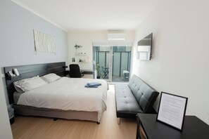Ein modernes Hotelzimmer mit Bett, Sofa, Schreibtisch und Balkon mit Blick.