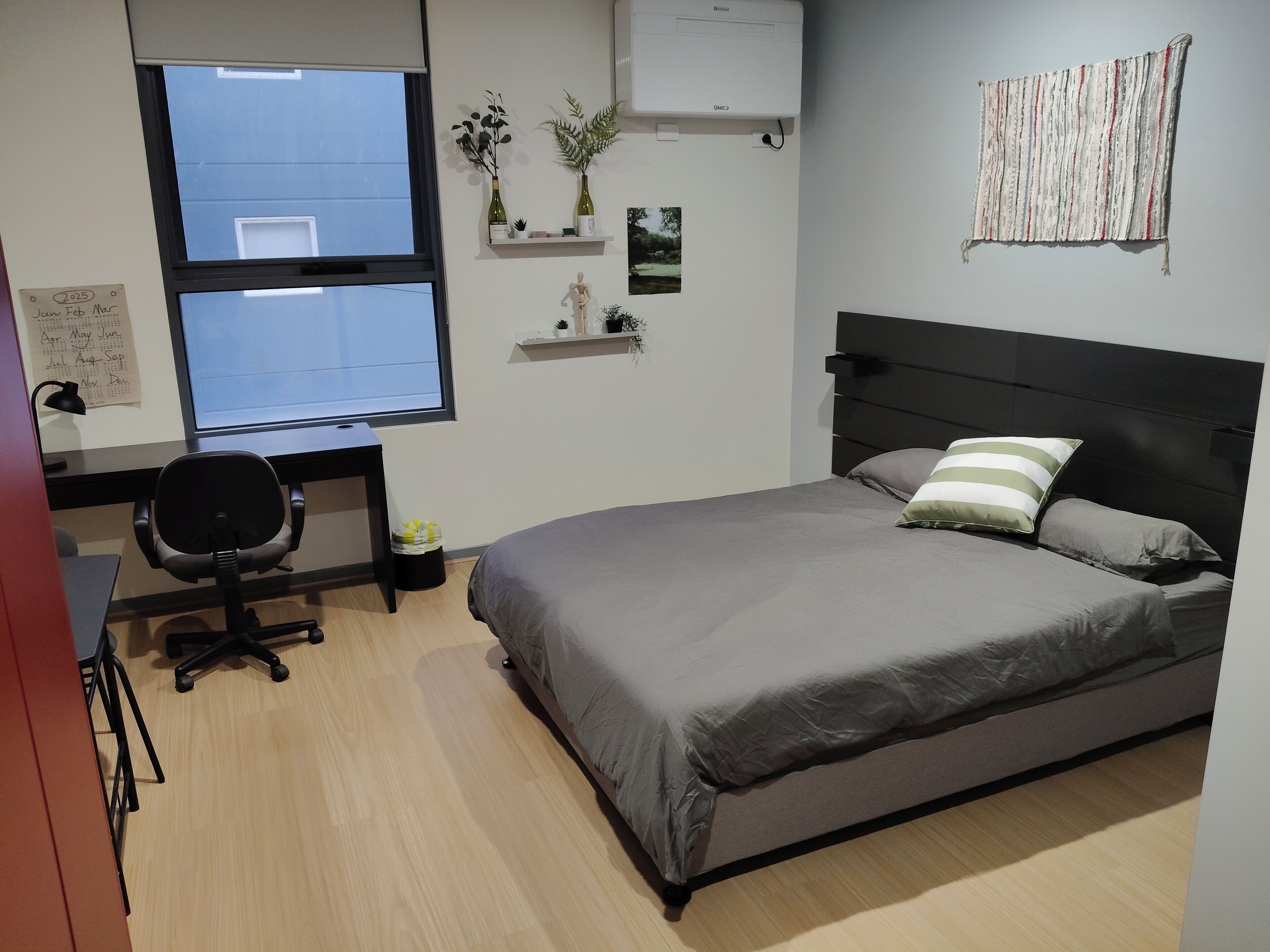 Een slaapkamer met een bed, een bureau en een stoel.