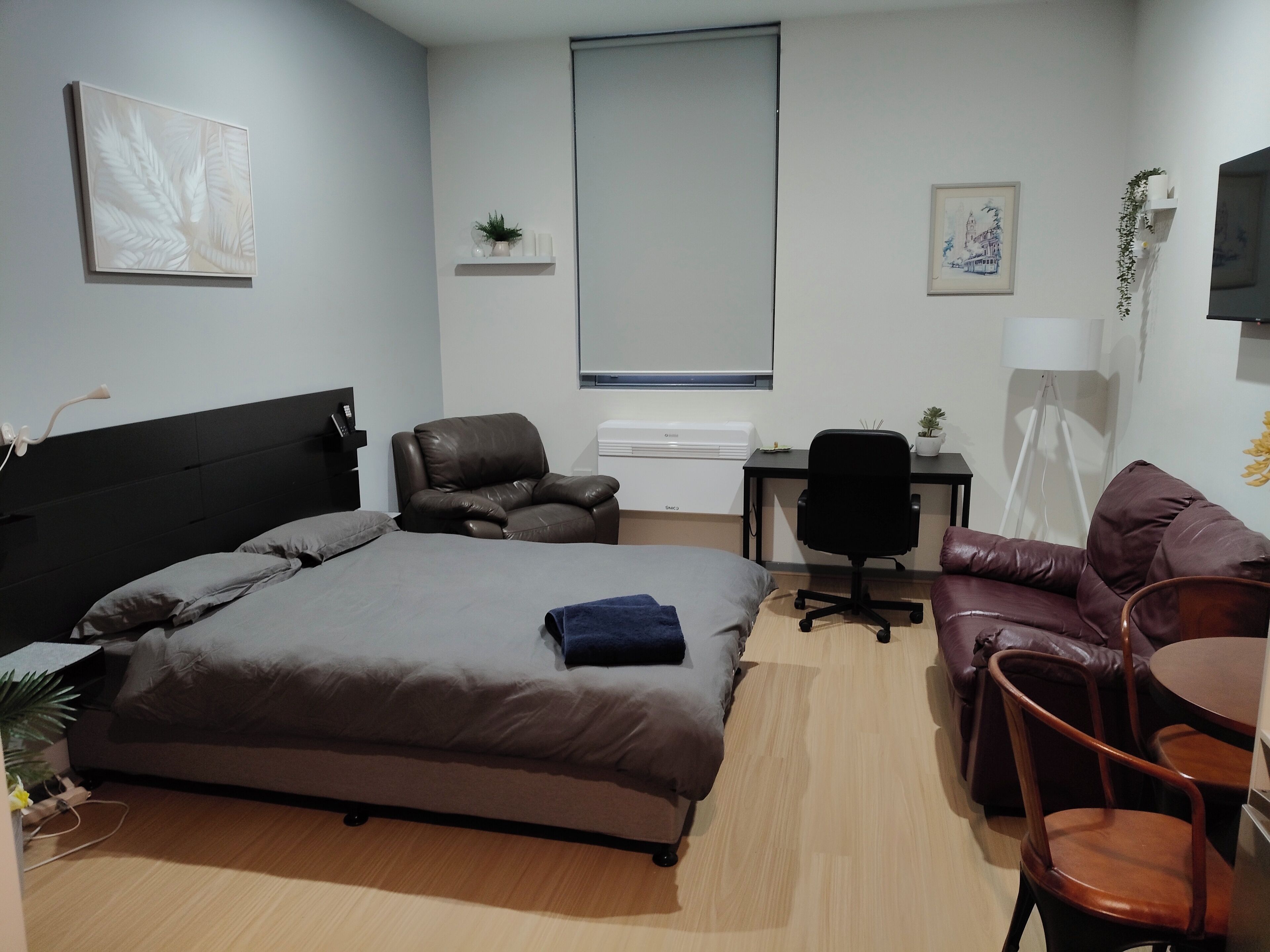 Un dormitorio moderno con cama, sillón de cuero, escritorio y sofá.