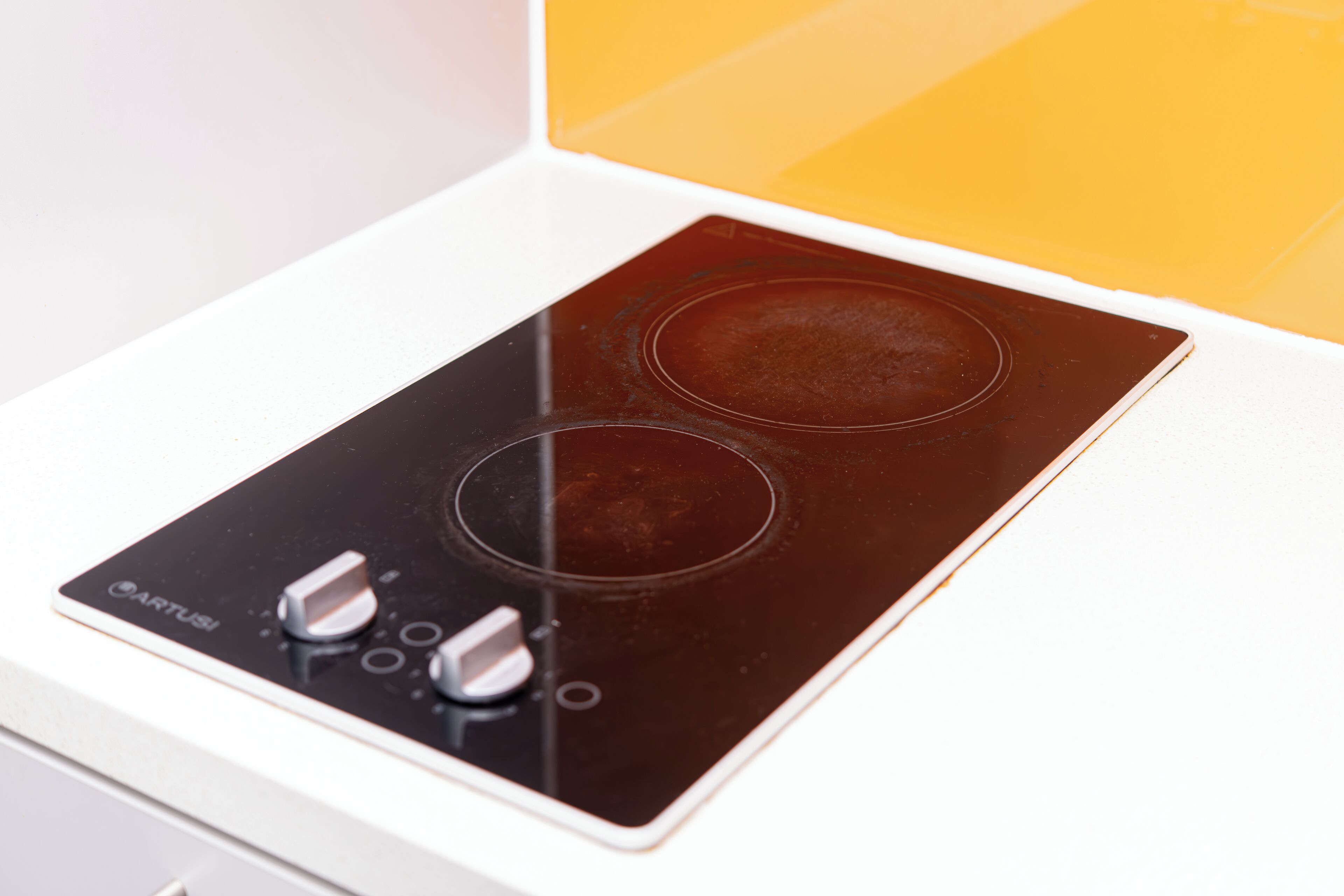 A kitchen with a black induction cooktop and a white countertop.