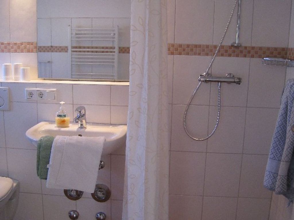 A bathroom with a sink, mirror, and shower.