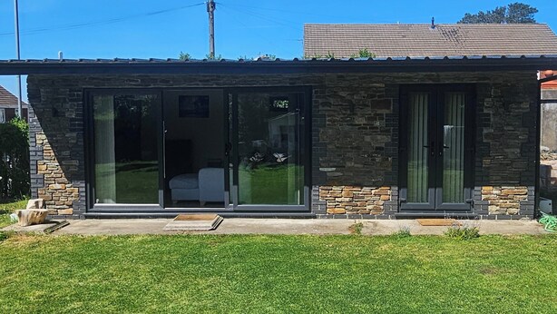 A modern building with a stone facade, large glass windows, and a flat roof. - 1bed Cottage, Sleeps 2 - Mountain Views, Parking (Neath)