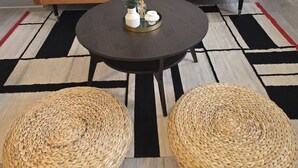Una sala de estar con sofá, mesa de centro y dos otomanas tejidas.