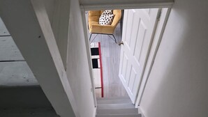 Una escalera con paredes blancas y una línea roja en el suelo que lleva a una puerta.