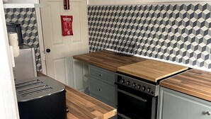 Una cocina compacta con horno integrado, tostadora y encimera de madera.