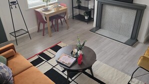 Una sala de estar moderna con un sofá, una mesa de centro, una zona de comedor con mesa y sillas, una estantería y una chimenea.